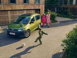 Ein Junge spielt Fußball vor einem goldenen VW-Caddy